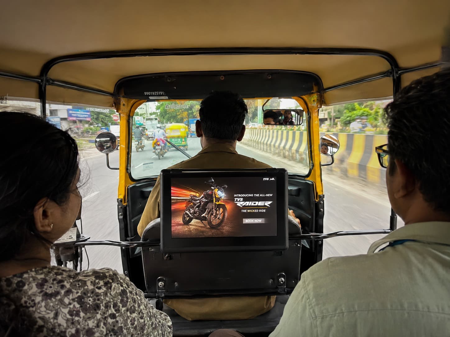 HappyFrU digital display mounted on an auto-rickshaw dashboard, playing a video ad to passengers