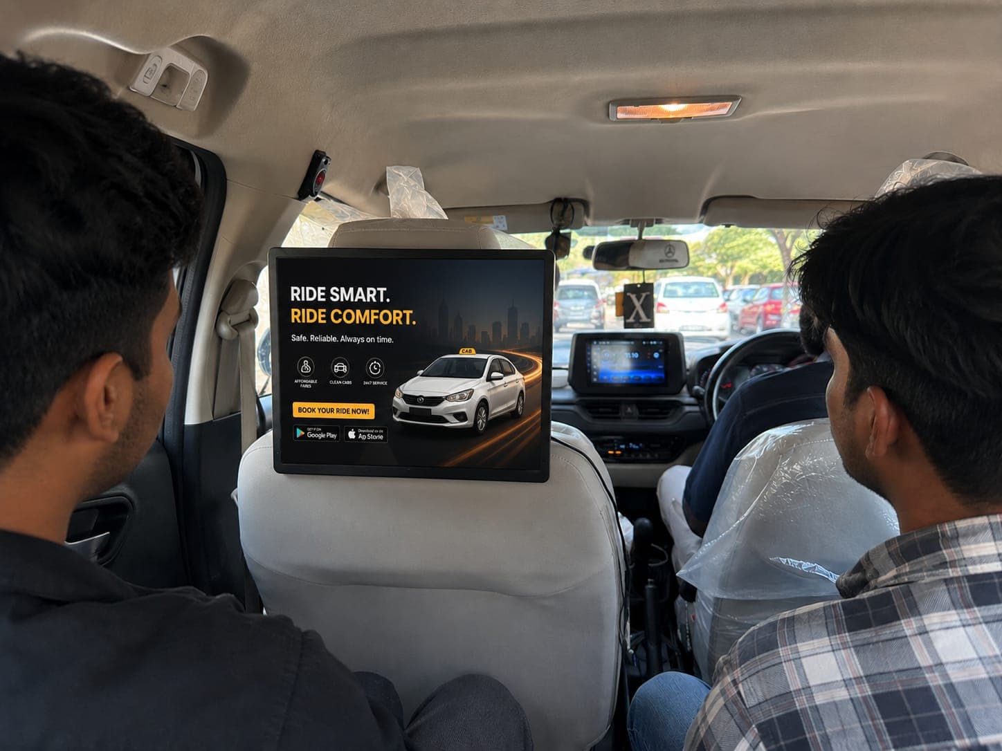 HappyFrU digital display mounted on a cab headrest, showing a ride comfort ad to rear passengers